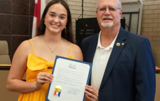 Anna Beck holds the Color the World Orange Day proclamation beside Foley Mayor Ralph Hellmich at a City Council meeting.
